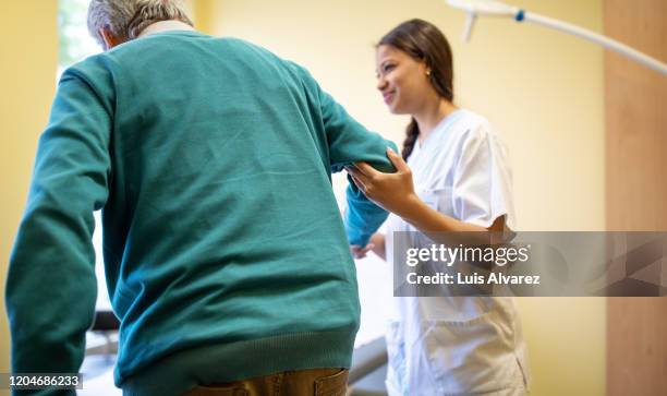 elderly patient being helped by a nurse in clinic - old trying to look young stock pictures, royalty-free photos & images