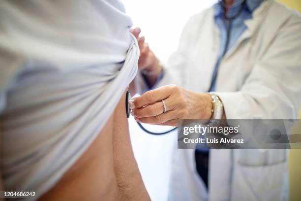 female doctor examining patient with stethoscope - arzt untersuchung stock-fotos und bilder