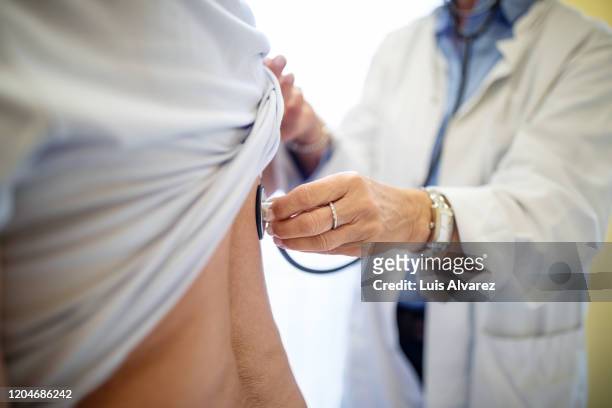 female doctor examining patient with stethoscope - visita fotografías e imágenes de stock