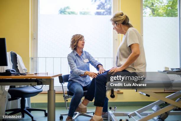 physiotherapist checking knee of female patient stock - hausarzt stock-fotos und bilder