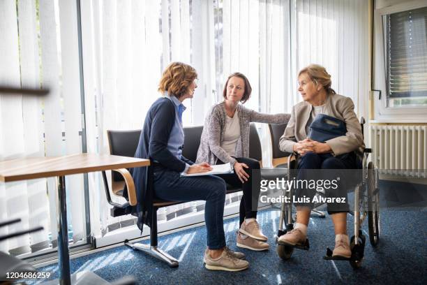 therapist discussing with women in waiting room - visiting patient in hospital stock pictures, royalty-free photos & images