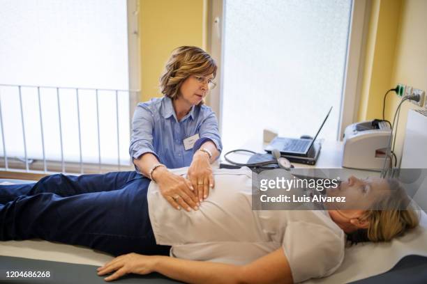 doctor checking patients stomach in a clinic - stomach stock pictures, royalty-free photos & images