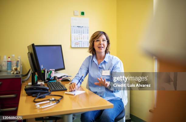 senior doctor talking with her patient in clinic - gp visit stock pictures, royalty-free photos & images