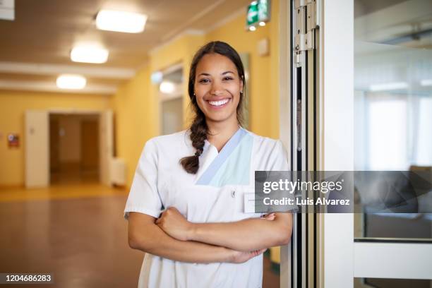 portrait of confident female nurse at doorway - arzt porträt stock-fotos und bilder