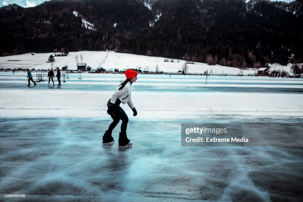 A woman ice skating on a frozen lake in winter