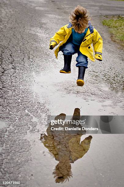 boy with reflection jumping in puddle - flaque photos et images de collection