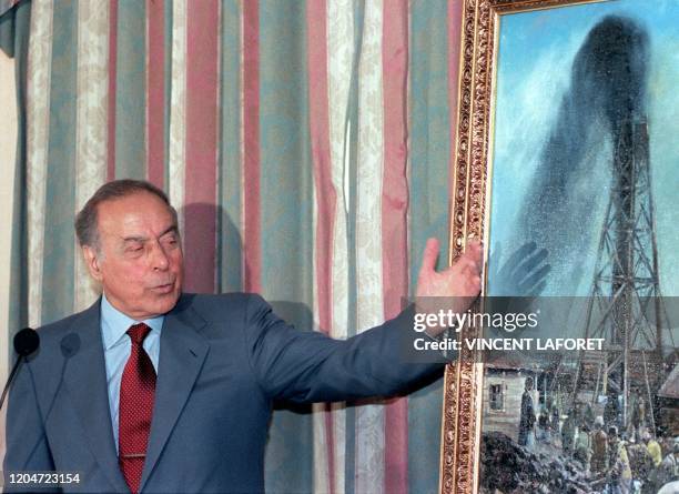 Azerbaijan President, Heydar Aliyev, points to a painting of one of the first oil wells in his country from 1848, which he later presented to the CEO...