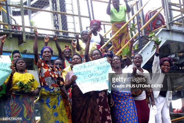 Gbaramatu women display 21 July 2002 their placards on Chevron oil flow station in Makarava in Gbaramatu, Warri-South, Niger Delta, to protest the...