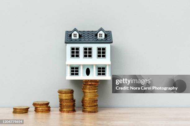 house model on top of stack of coins - property prices continue to increase stock-fotos und bilder