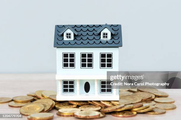 model house on top of gold coins - hausmodell stock-fotos und bilder