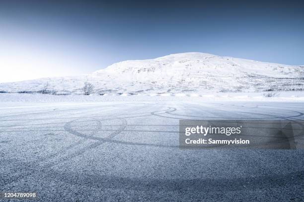 icy road against snowcapped mountain - winter road stock pictures, royalty-free photos & images