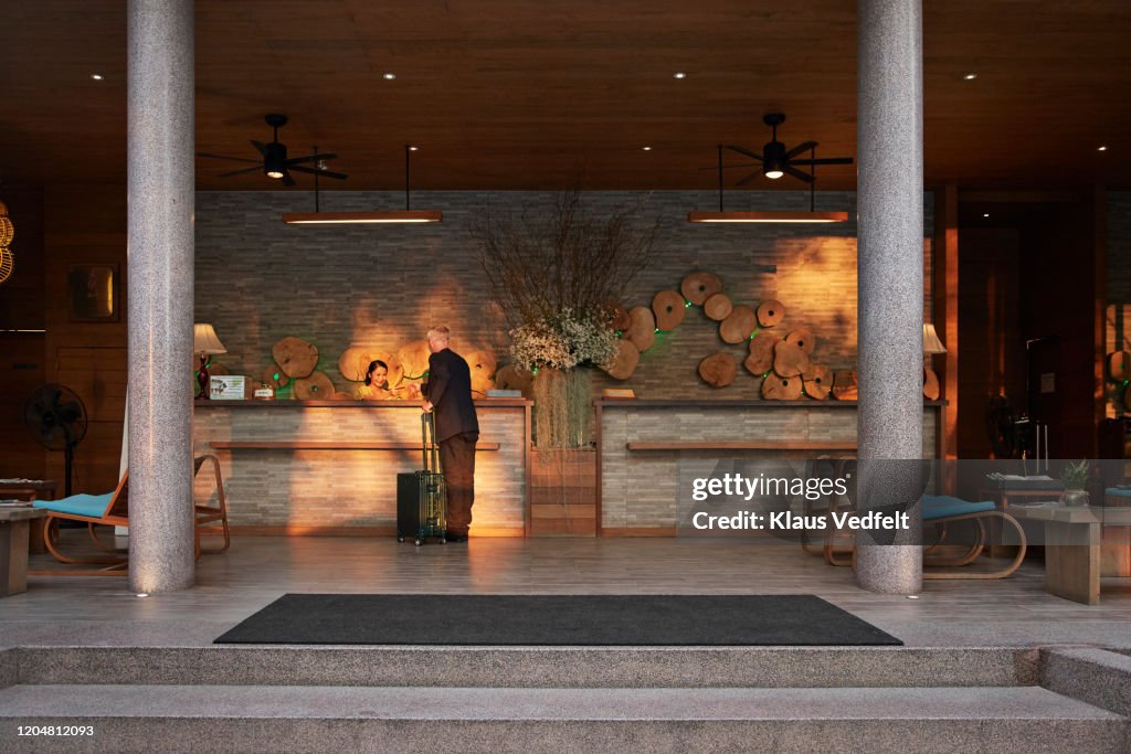 Male tourist talking to receptionist at counter