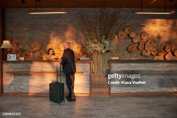 man giving passport to receptionist in lobby - receptionist fotografías e imágenes de stock