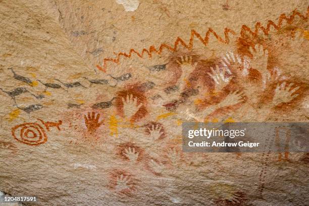 closeup shot of prehistoric paintings of hands and animals on cliff wall. - cave art stockfoto's en -beelden