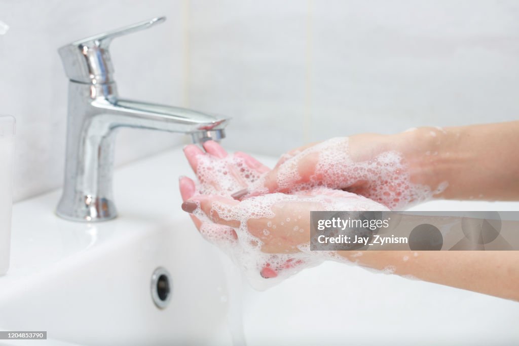 Primer plano de una mujer lavándose las manos en el fregadero