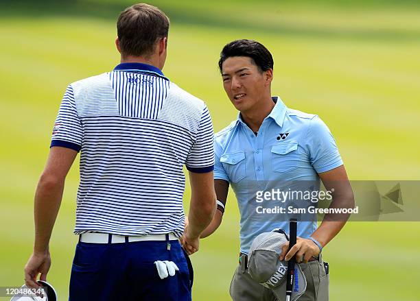 Nick Watney and Ryo Ishikawa of Japan shake hands on the 18th hole after finishing their third round of the World Golf Championships-Bridgestone...