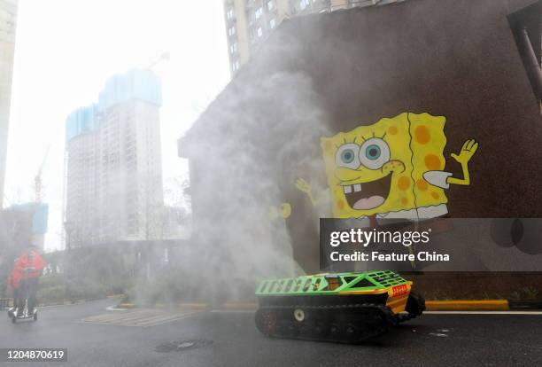 Remotely-controlled vehicle disinfecting an apartment complex passes by an image of Sponge Bob in Wuhan in central China's Hubei province Tuesday,...