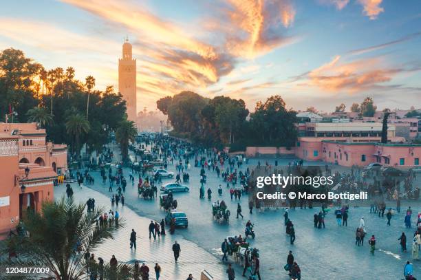 the koutoubia mosque's minaret and tourists in djemaa el fna square at sunset, marrakech, morocco - djemma el fna square 個照片及圖片檔