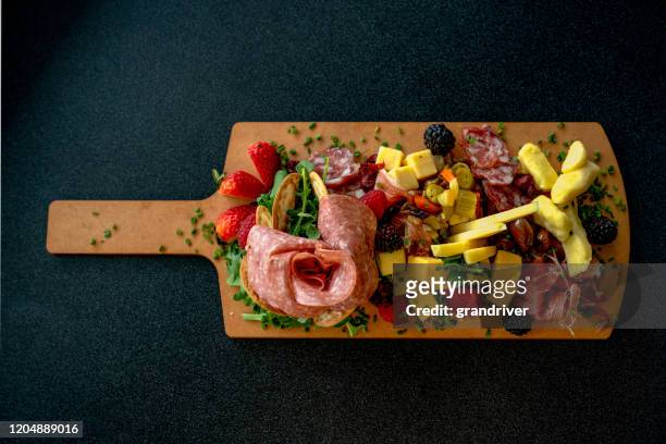 een charcutierie schotel die met een verscheidenheid van vlees, kazen en fruit wordt geschikt - charcuterie stockfoto's en -beelden