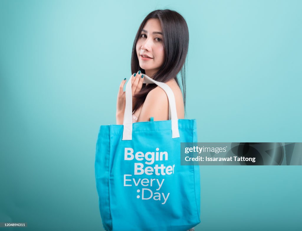 Woman with cotton bag,canvas tote bag isolated on white brick wall.
