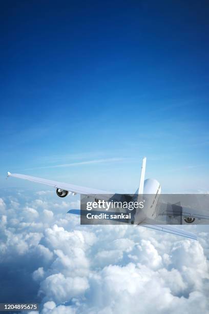 weißes passagierflugzeug fliegt über wolken - flugzeug seitlich himmel stock-fotos und bilder