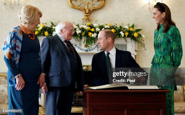 Prince William, Duke of Cambridge sings a visitors book next to his wife Catherine, Duchess of Cambridge, as they meet with Ireland's President...