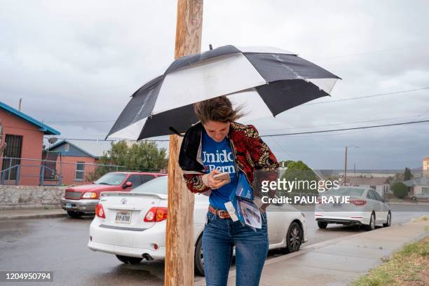 Olivia DiNucci, volunteer for the Bernie Sanders campaign, stands with an umbrella under the rain as she hands out pamphlets on the day of the...