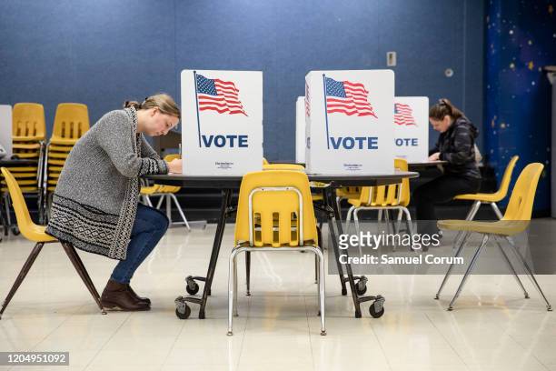 Two women mark down their votes on a ballots for the Democratic presidential primary election at a polling place in Armstrong Elementary School on...