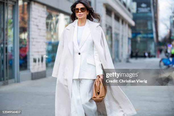 Victoria Barbara is seen wearing white Jil Sander suit, Max Mara white coat, brown Bottega Veneta pouch bag, Celine sunglasses during New York...