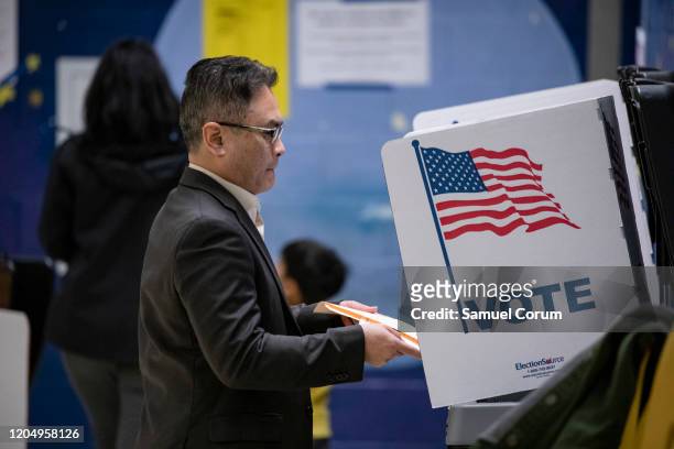 Voter casts his ballots into a voting machine for the Democratic presidential primary election at a polling place in Armstrong Elementary School on...