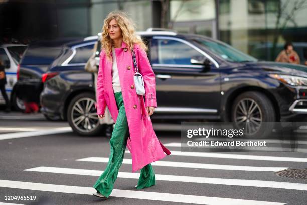 Emili Sindlev wears a pink crocodile pattern coat, a white bag, green snake print flared pants, a white top, outside Self Portrait, during New York...