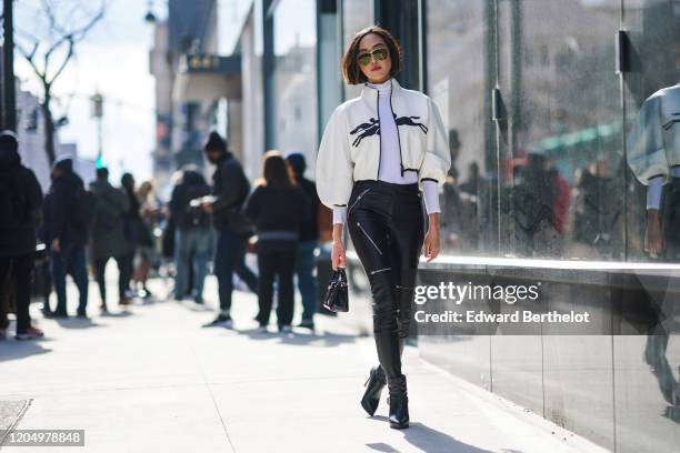 Chriselle Lim wears sunglasses, a Longchamp white jacket with puff sleeves, a white top, black leather pants, a bag, outside Longchamp, during New...