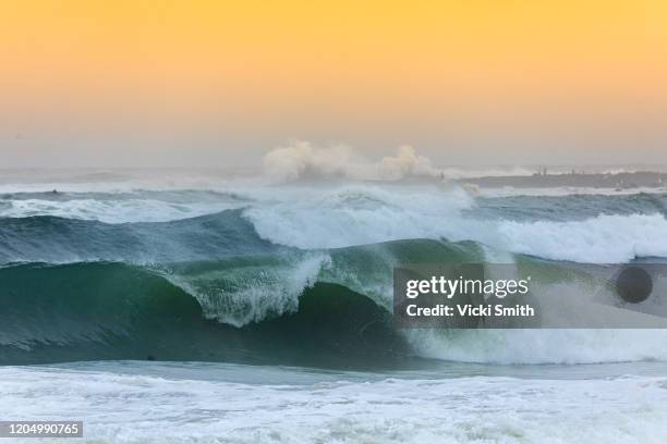 large curled stormy ocean wave about to break with yellow skys at sunset - gold coast wave stock pictures, royalty-free photos & images