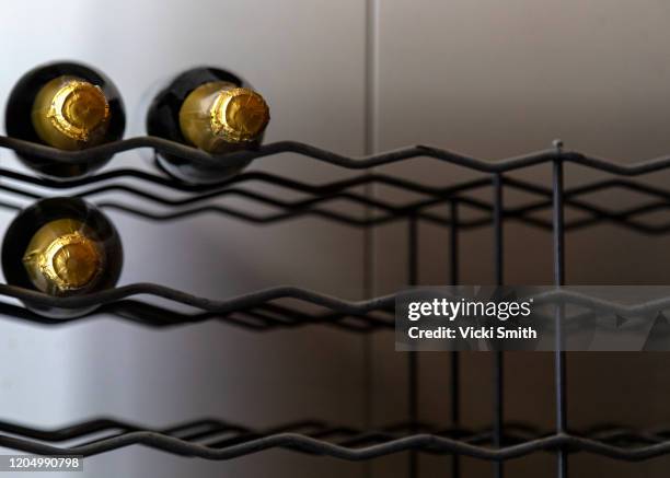 three golden champagne bottle tops in a wine rack - wine rack stock pictures, royalty-free photos & images