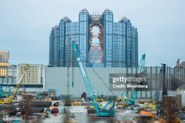 Cranes operate at a construction site in front of the Studio City casino resort, developed by Melco Crown Entertainment Ltd., in Macau, China, on...