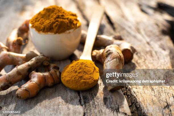 turmeric roots with turmeric powder on wooden background - ginger stock-fotos und bilder