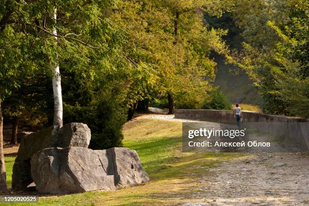 a girl walks along a path on a sunny autumn day in the valley of acquafraggia waterfalls in borgonuovo - valchiavenna, italy - acqua splash ストックフォトと画像