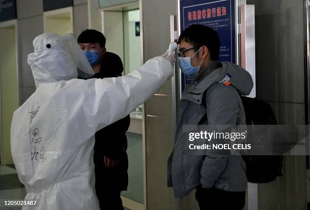 Passenger wearing a face mask has his temperature checked at the railway station in Hefei, China's eastern Anhui province on March 4, 2020. - China...