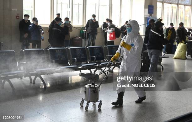 Worker wearing a protective suit disinfects the departure area of the railway station in Hefei, Chinas eastern Anhui province on March 4, 2020. -...