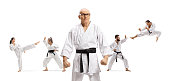 Elderly karate master with black belt posing with people exercising behind