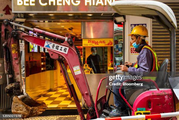 Construction worker wearing a protective mask sits on a mini excavator in front of a Bee Cheng Huang store at Senado Square in Macau, China, on...