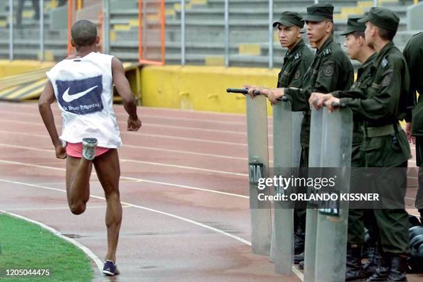 Colombian police officers watch an athlete run 11 July 2001 during a break from training in a simulated bomb threat at the Pascual Guerrero stadium,...