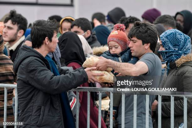 Migrants who arrived to the island of Lesbos in the last few days and camp in the port of Mytilene, queue for food distribution on March 4, 2020. - A...