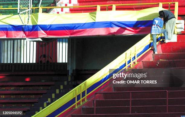 Workers hang Colombian flags at Nemesio Camacho "El Campin" Stadium 27 July 2001 in Bogota, two days before the Copa America final between Mexico and...