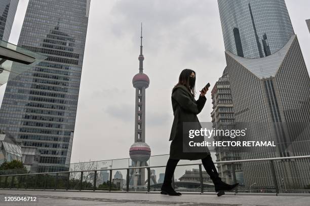 Woman wearing a face mask walks across a bridge in the financial district of Lujiazui in Shanghai on March 4, 2020. - China on March 4 reported 38...