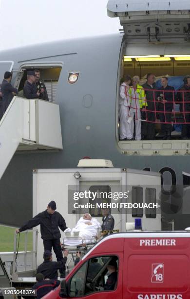 Un des 12 blessés français est transporté dans une ambulance, le 09 mai 2002, sur le tarmac de l'aéroport d'Orly. Blessés la veille dans...