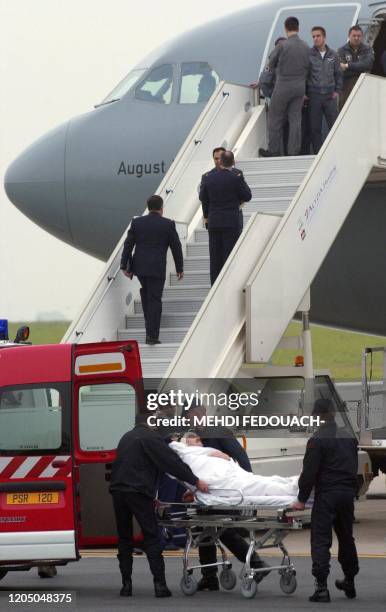 Un des 12 blessés français est transporté dans une ambulance, le 09 mai 2002, sur le tarmac de l'aéroport d'Orly. Blessés la veille dans...