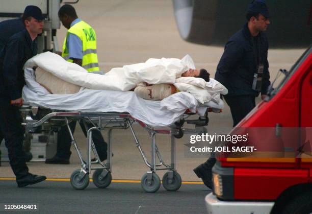 Un des 12 blessés français de l'attentat de Karachi au Pakistan, est transporté vers une ambulance, le 09 mai 2002, sur le tarmac de l'aéroport...