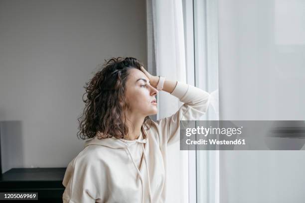 portrait of pensive woman looking out of window - hand in hair imagens e fotografias de stock