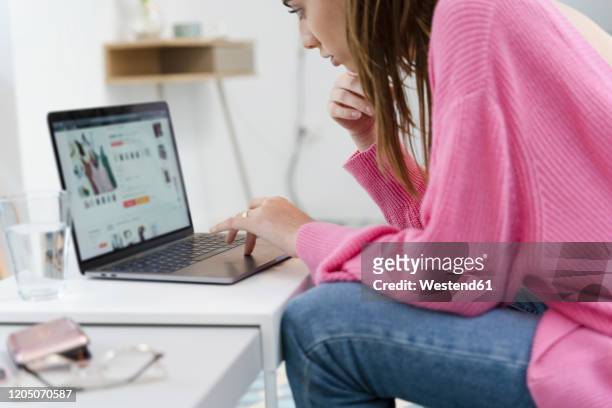 young woman sitting on the couch using laptop - internet shopping stock-fotos und bilder
